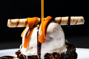 házi karamell, barna folyadék csorog fehér gombócon fekete háttér előtt