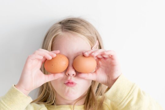 szőke lány két tojást tart a szemei elé