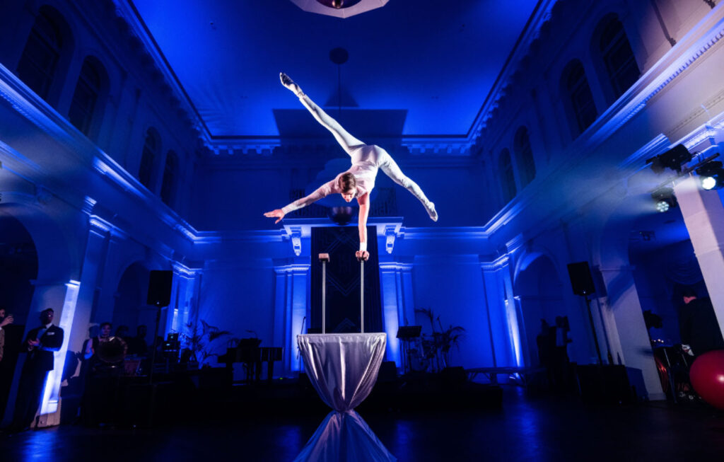 kéken bevilágított teremben egy akrobata mutat be gyakorlatot