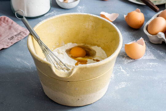 palacsinta, tojás és liszt egy barna edényben habverővel