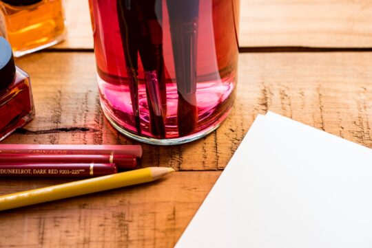 bor és művészet, színes ceruzák és egy üveg barna asztalon