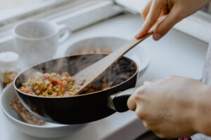 serpenyő és fakanál egy nő kezében