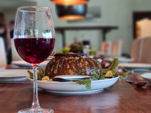 talpas pohárban piros folyadék, mögötte tányéron hús