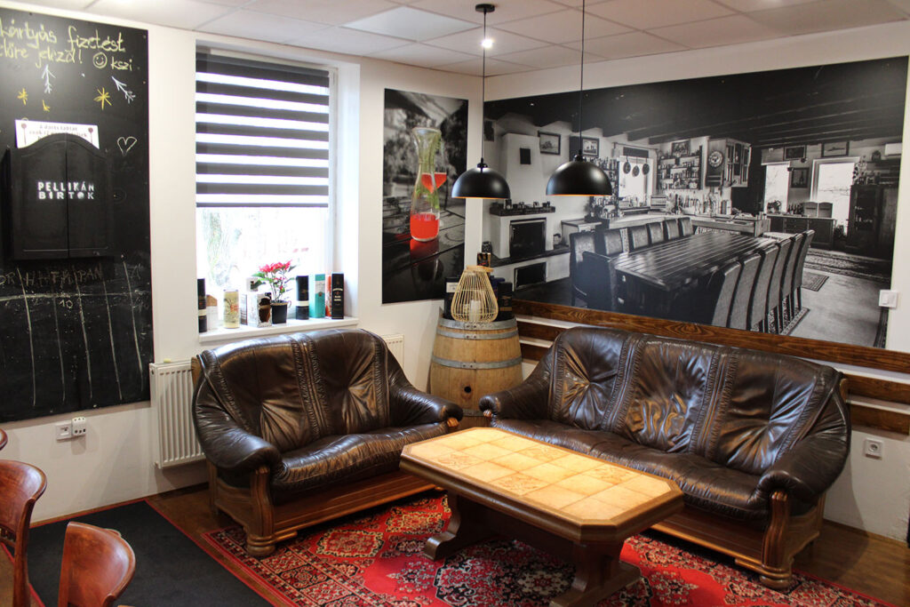 helyiség, a falon képekkel, elől barna fotelekkel