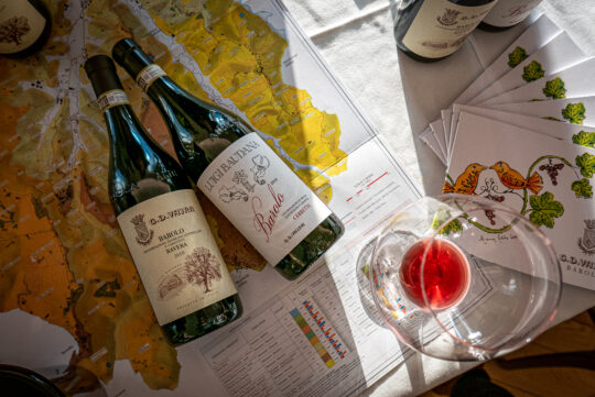 két palack nebbiolo bor fektetve egy térképen, mellette egy pohárban nebbiolo bor