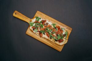 pizzatészta, színes pizza vágódeszkán fekete háttér előtt