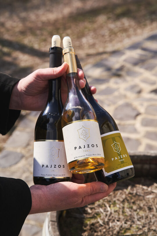 két kéz három palack bort tart, köztük van egy tokaji aszú