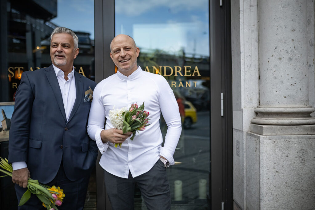 két férfi áll a st. andrea restaurant üvegajtaja előtt