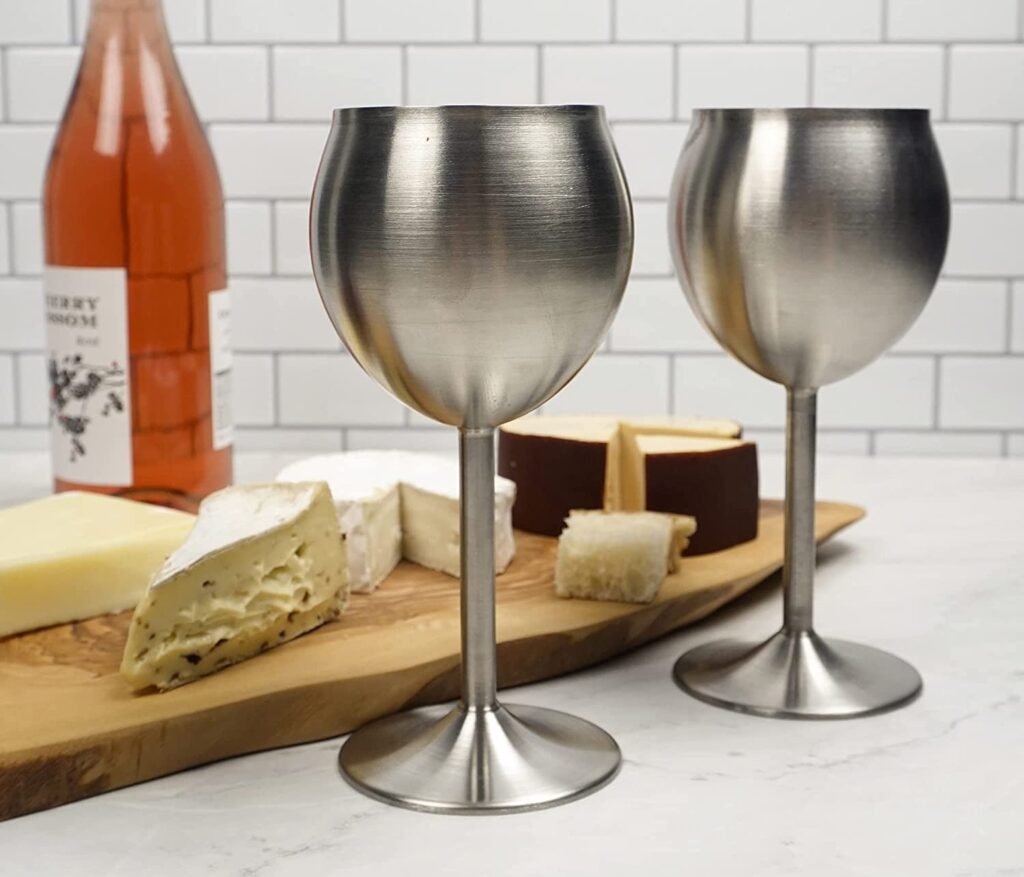 egy palack rozé, sajtok fa tálcán és két fém boros pohár kupa