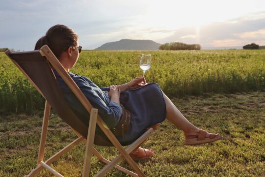 egy nő ül a nyugágyban, kezében bor