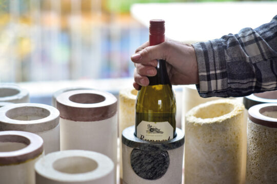 egy kéz egy palack bort vesz ki egy beton borhűtőből