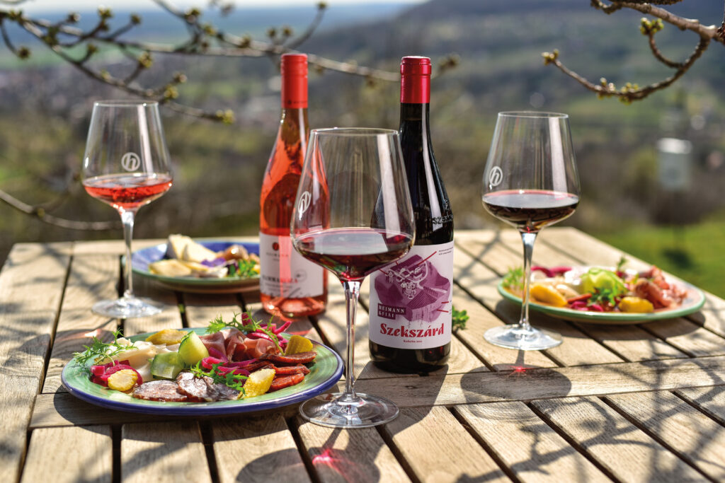 egy asztalon Heimann borok és finom ételek a szabadban