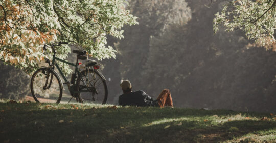 férfi ül a fűben, mellette bicikli