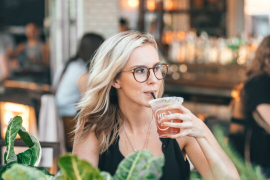 szemüveges szőke nő szívószállal iszik pohárból