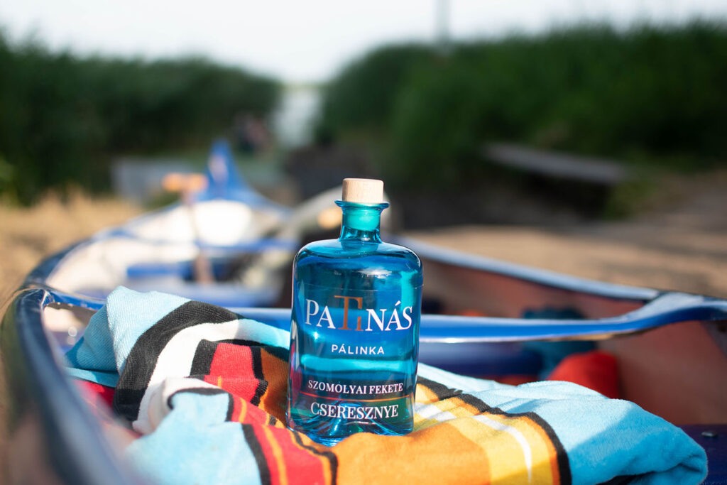 kék patina pálinka üveg egy csónakban, színes terítőn
