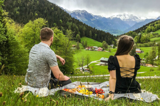 piknik, két ember ül egy pokrócon a hegyek között