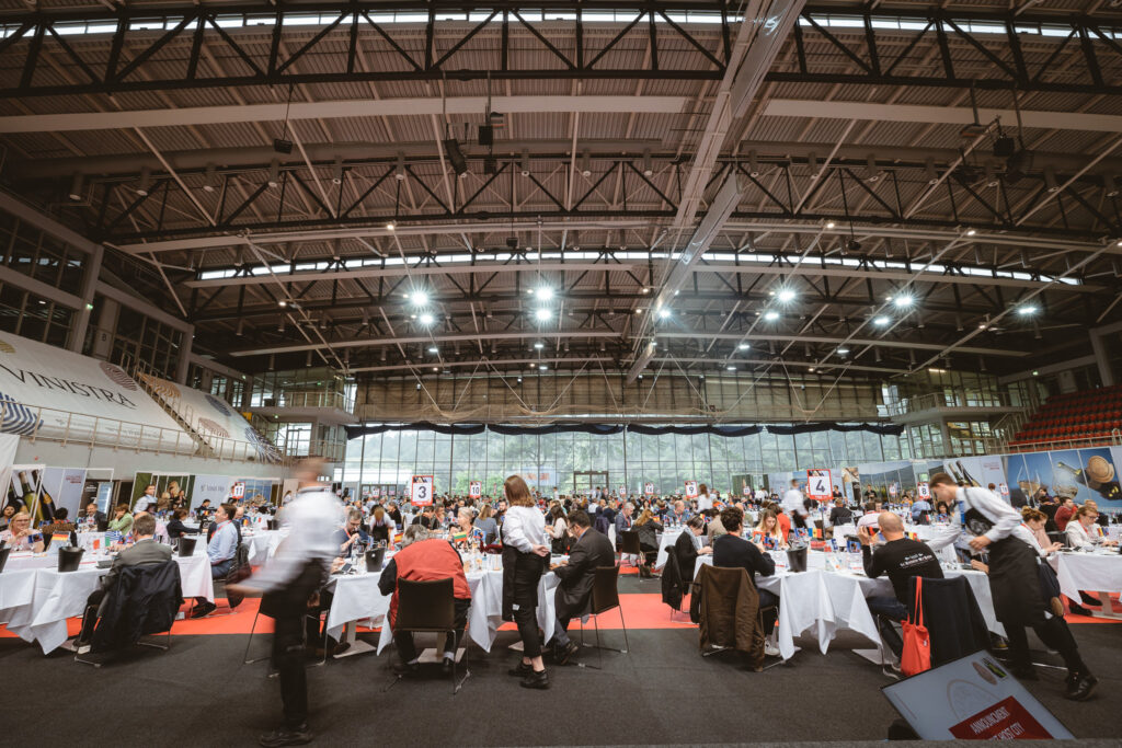 emberek ülnek asztaloknák egy csarnokban a Concours Mondial de Bruxelles borversenyen