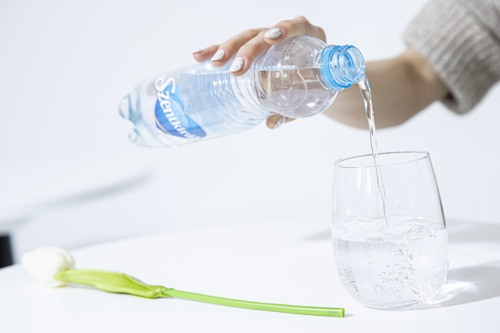 szentikirályi ásványvizes palackból töltenek vizet pohárba