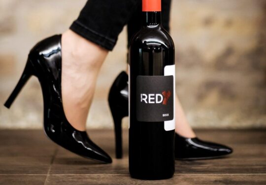 magassarkú cipő előtt egy palack REDy bor