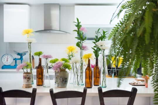 egy asztalon különböző üvegekben virágok