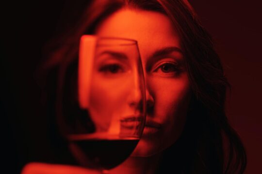 hosszú hajú nő poharat tart a kezében, benne bor