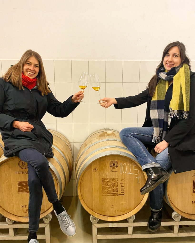 két lány ül boros pohárral a kézben a boros hordón