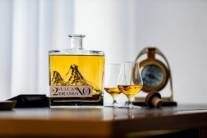 átlátszó üvegben barna folyadék, mellette két pohár