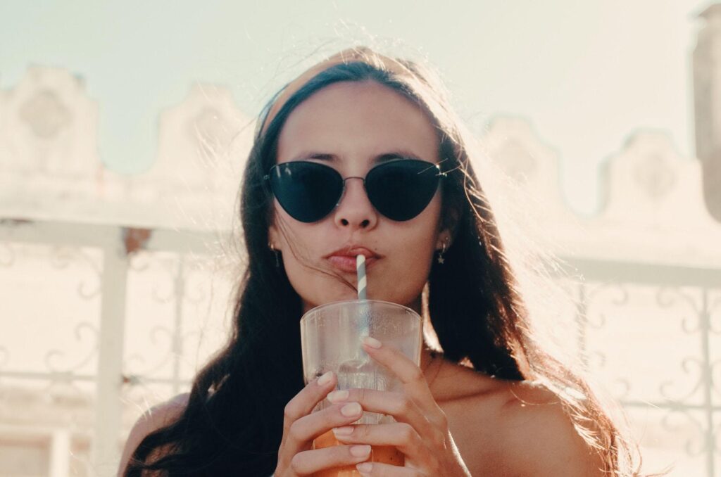 nő kezében pohár, szívószállal iszik