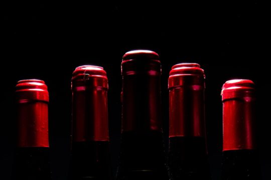 vörösbor palackok teteje piros fóliával, fekete háttér