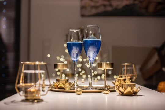 kék ital átlátszó talpas pohárban egy megterített asztalon