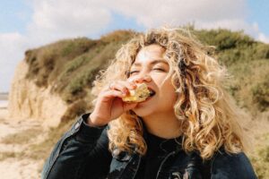 szőke nő kezében szendvics, eszik