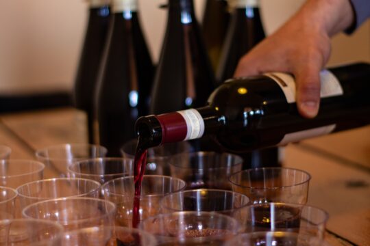 egy kéz vörösbort tölt poharakba