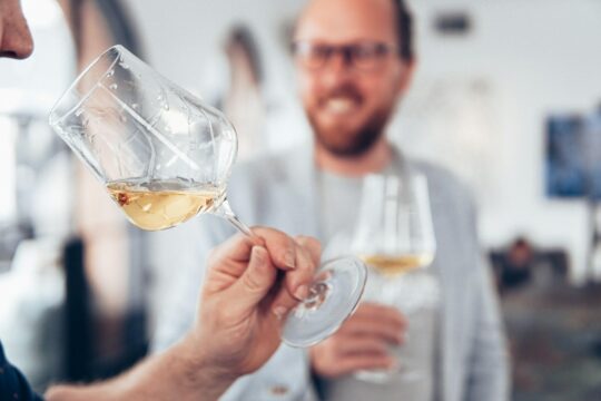 két férfi fehérbort kóstol talpas pohárból