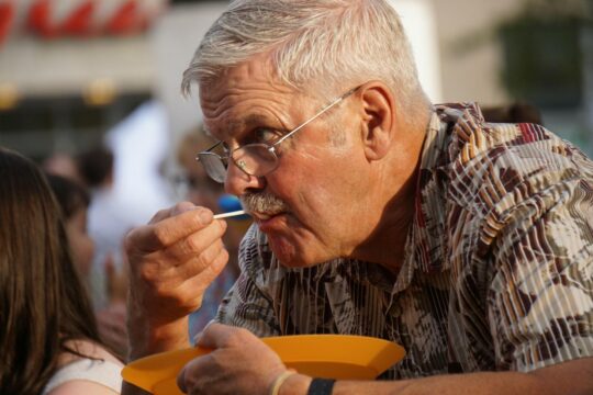 férfi eszik kanállal sárga tányérból