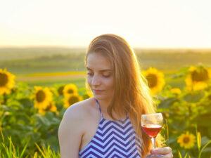 napraforgók előtt egy nő, kezében borospohár