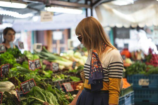 nő nézelődik a piacon, zöldségek között áll