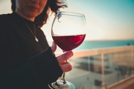 egy nő egy pohár vörösbort tart a kezében