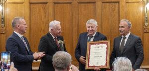 négy férfi áll a fal előtt, bock józsef oklevelet tart a kezében